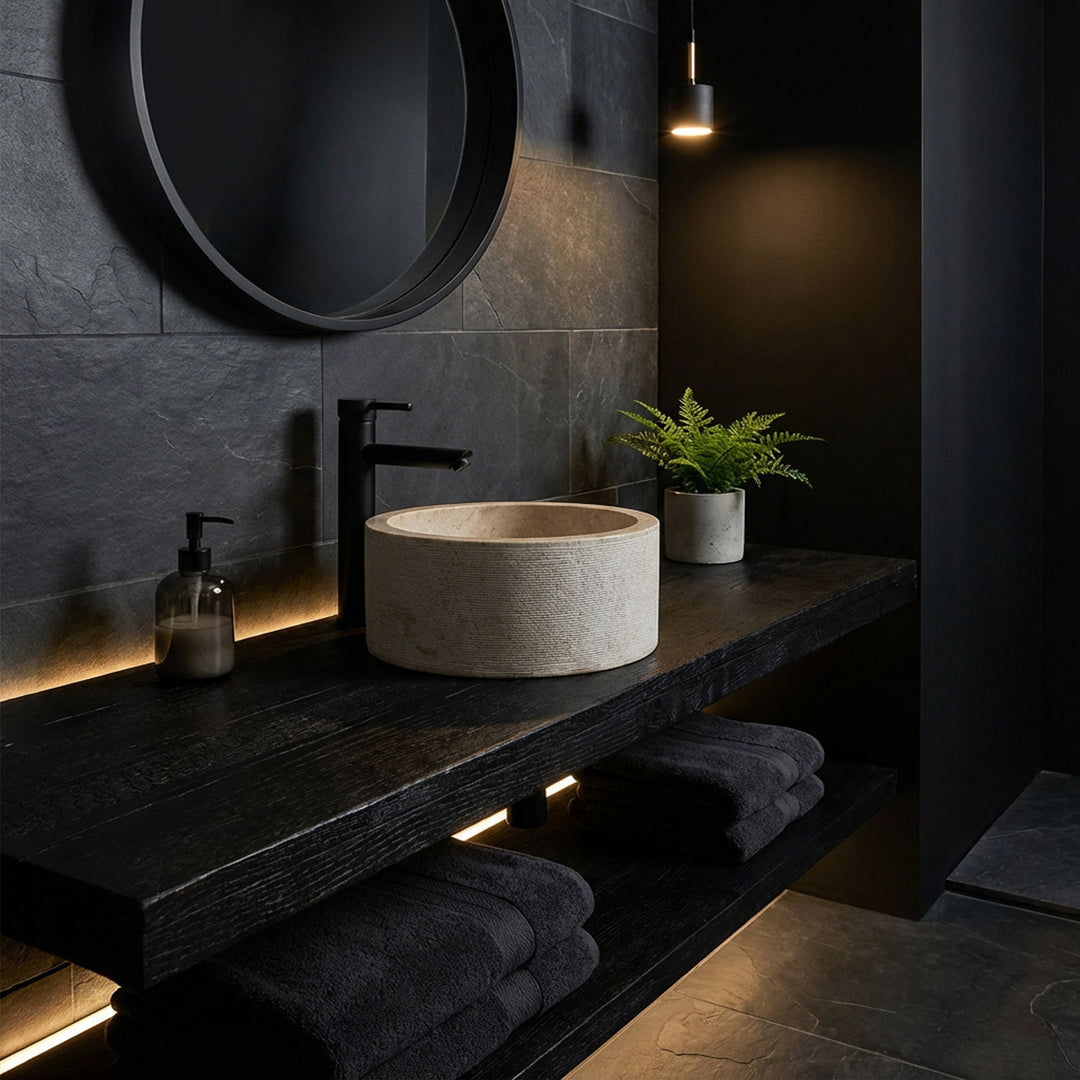 Rundes Aufsatzwaschbecken in edler Marmoroptik auf dunkler Holzkonsole, inszeniert im minimalistischen Dark-Mood-Bad.