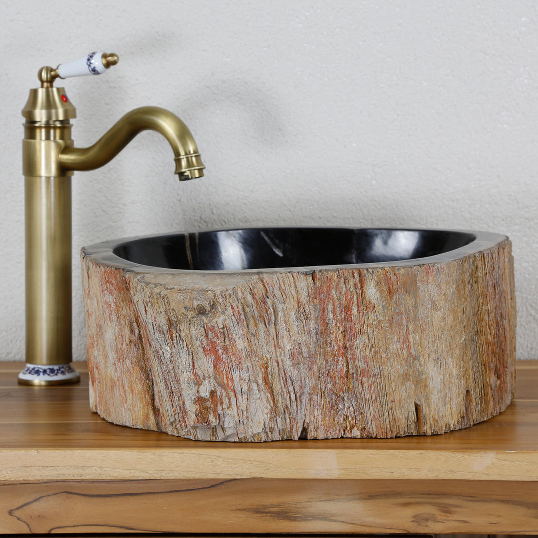 Waschbecken aus fossilem Holz mit markanter Außenstruktur, rundes Steinwaschbecken auf Holzplatte kombiniert mit Messingarmatur.