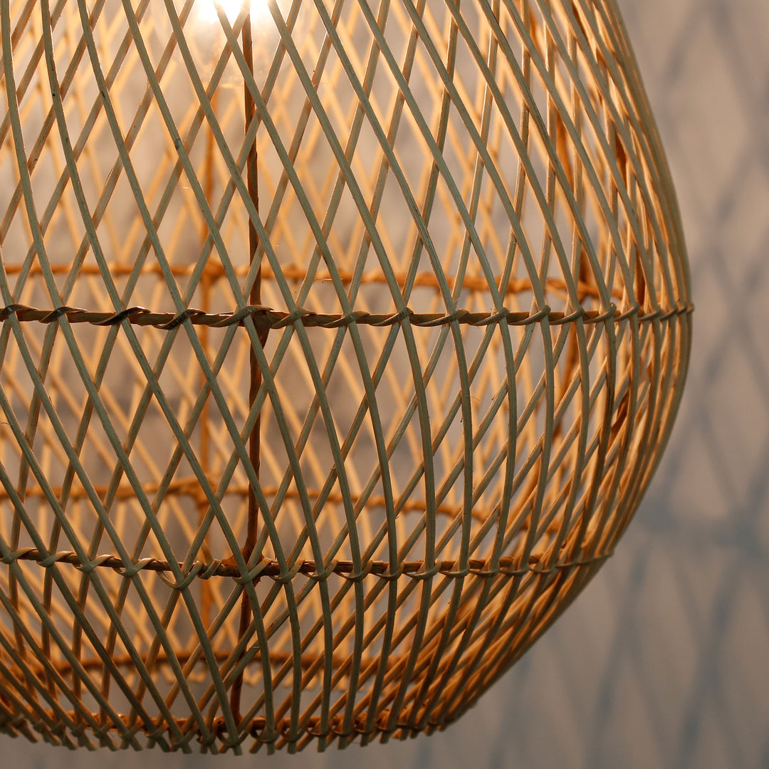 Detailaufnahme einer handgefertigten Rattanlampe mit feinem, diagonalem Flechtmuster und warmem Lichtschein