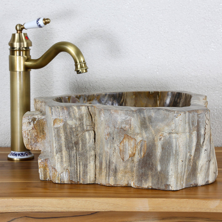 Naturstein Waschbecken aus versteinertem Holz mit markanter Fossilstruktur auf Holzplatte, kombiniert mit Messing-Armatur